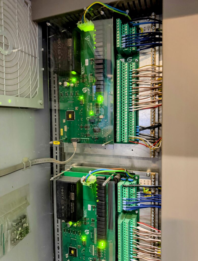 Modules électroniques et équipements de commande installés dans une armoire d'automatisation avicole.