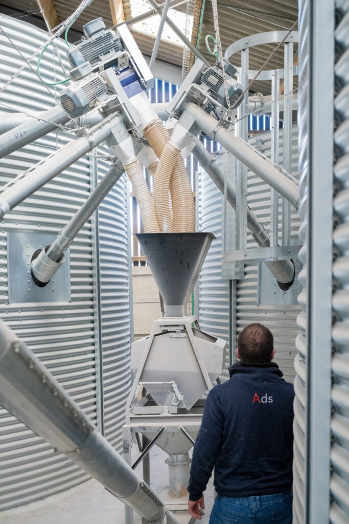 Trémie de manutention des céréales avec équipements de transfert et silos métalliques à Dinant.