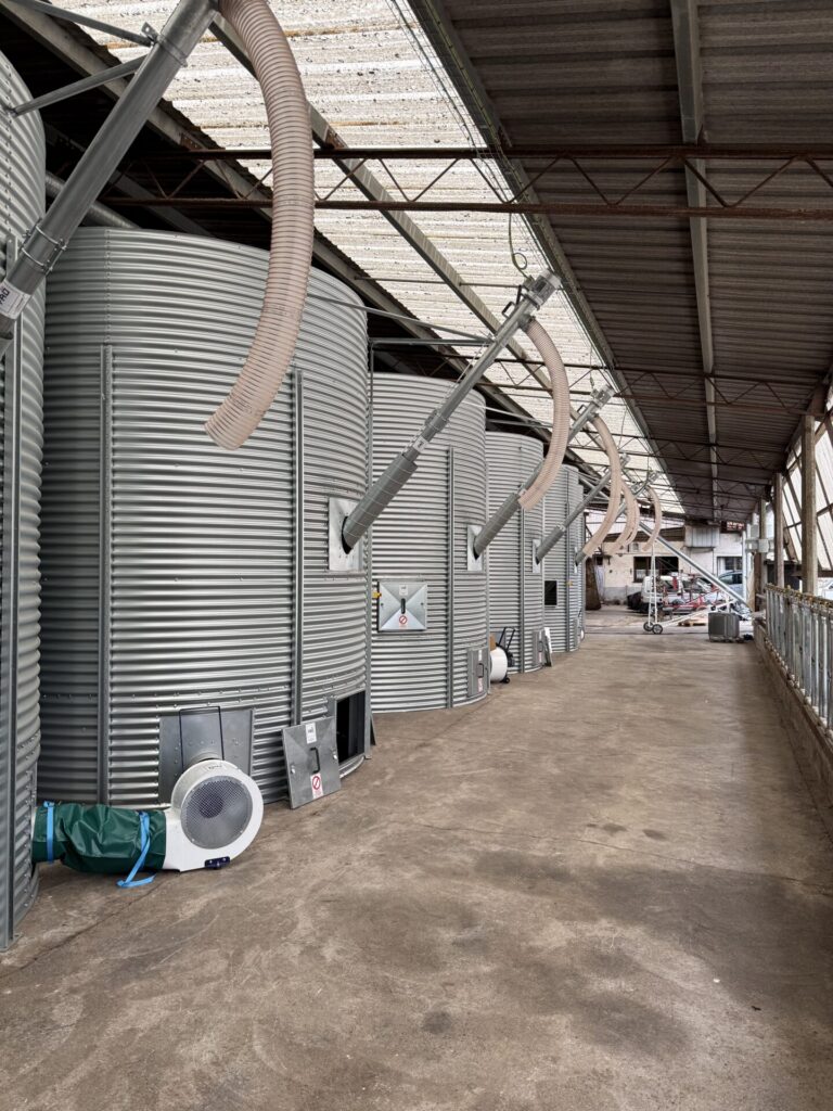 Installation de stockage de céréales avec silos métalliques et équipements de manutention des grains.